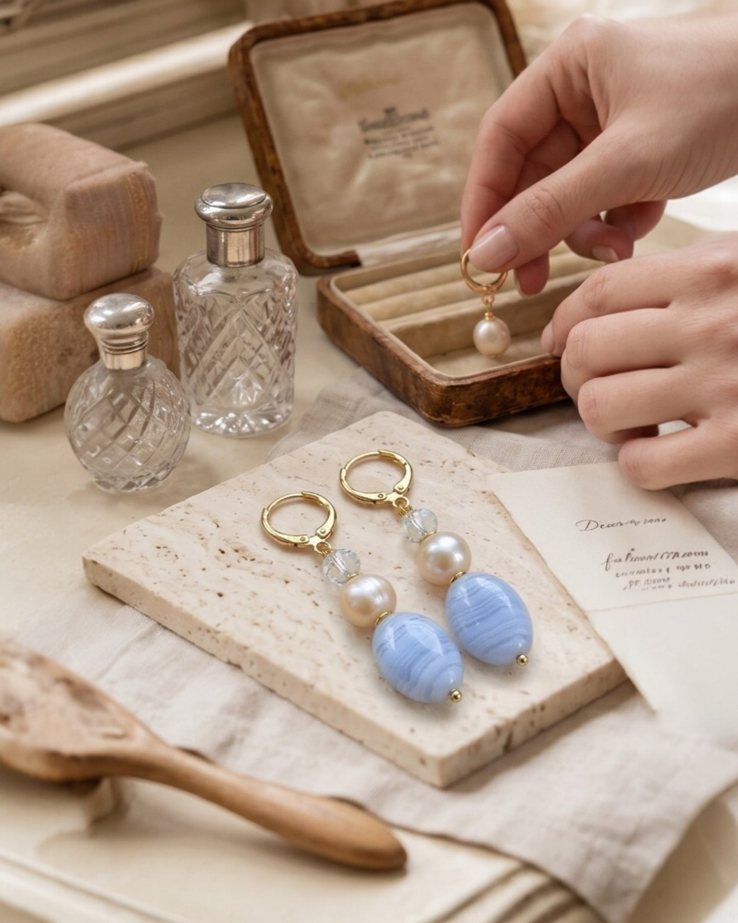 Brincos Duna Azul (Kék) da Körössy — semijoia banhada a ouro 18k com ágata blue lace, pérola e cristal austríaco, feitos à mão.