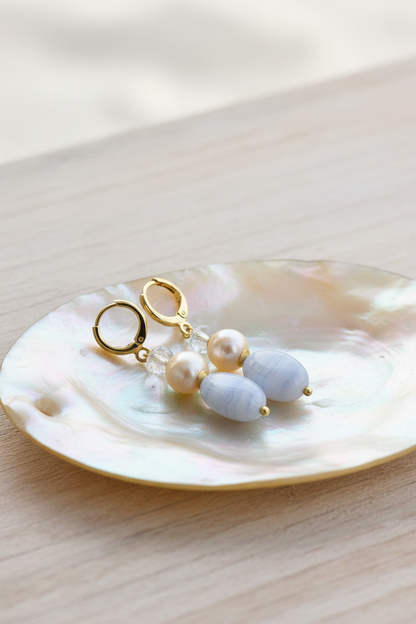 Brincos Duna Azul (Kék) da Körössy — semijoia banhada a ouro 18k com ágata blue lace, pérola e cristal austríaco, feitos à mão.
