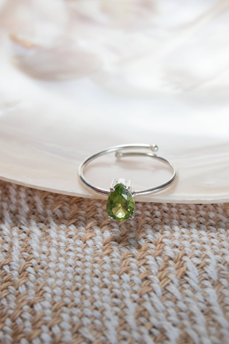Anel KÖRÖSSY | Joias e Semijoias delicadas e autorais em prata 925 com peridoto verde luminoso lapidado em gota, tamanho ajustável.