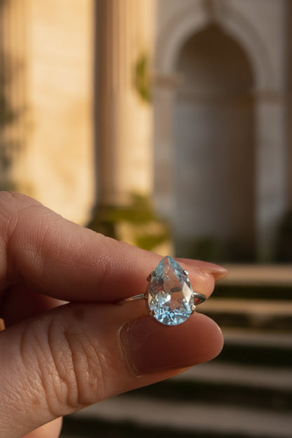 Anel KÖRÖSSY | Joias e Semijoias delicadas e autorais em prata 925 com topázio azul lapidado em gota, estilo delicado e luminoso.