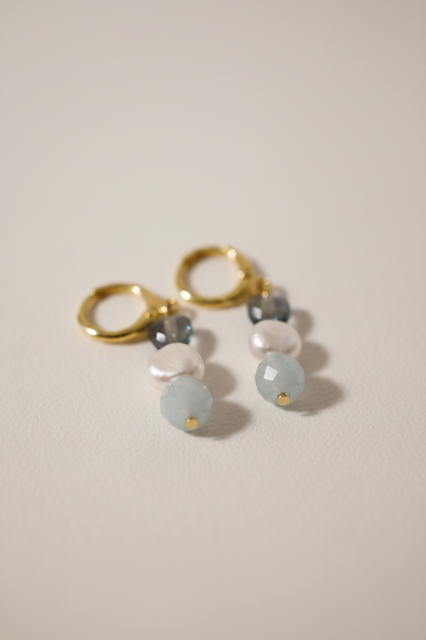Brincos Duna Sopro (Lehelet) da Körössy — semijoia banhada a ouro 18k com água-marinha, pérola e cristal austríaco, feitos à mão.